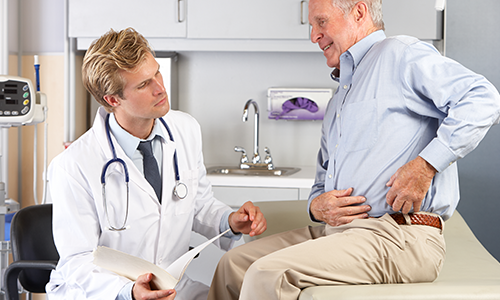 An older man describing his hip pain to his doctor.