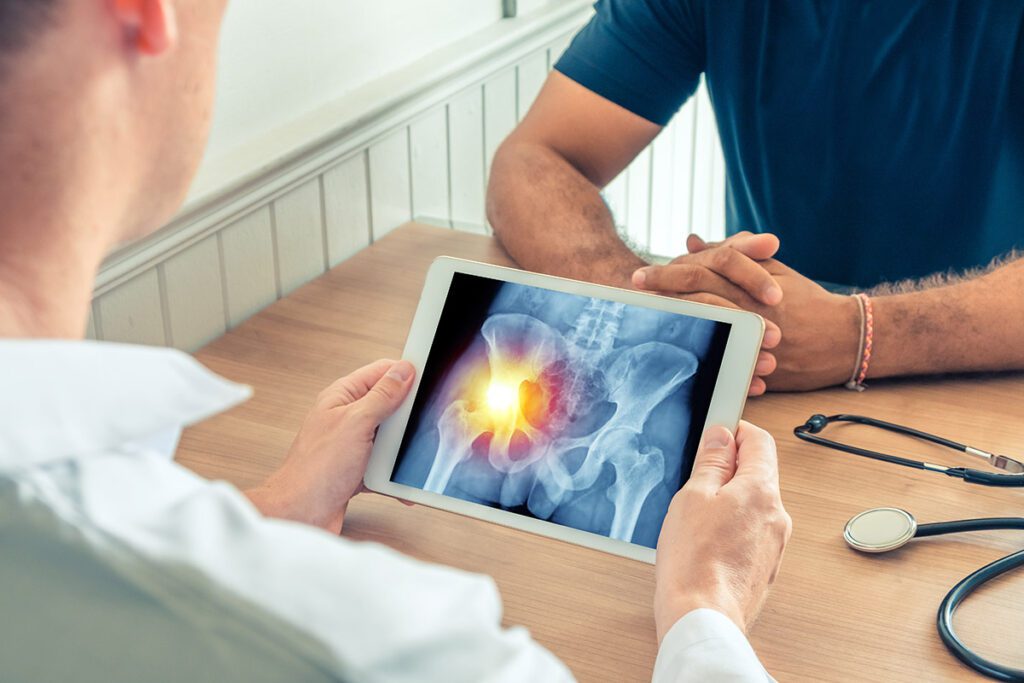 Doctor holding a digital tablet with x-ray of hips of the patient.